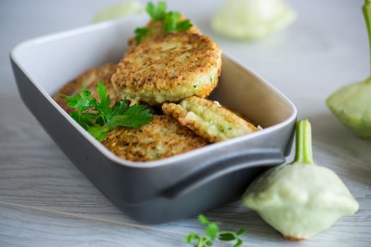 vegetable fried squash and zucchini cutlets in a ceramic form on a light wooden table