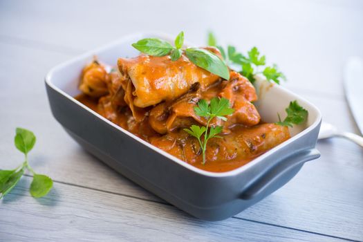 Traditional stuffed cabbage with minced meat and rice, served in a tomato sauce on a wooden table .