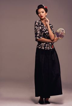 Honoring her family name. Studio shot of an attractive young woman dressed in traditional asian clothing