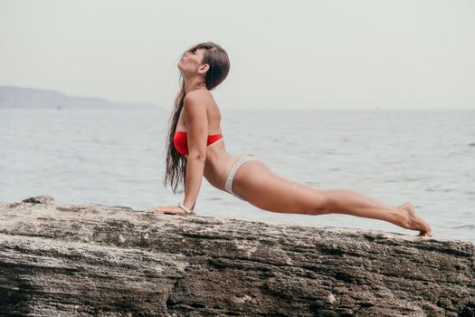Woman meditating in yoga pose silhouette at the ocean, beach and rock mountains. Motivation and inspirational fit and exercising. Healthy lifestyle outdoors in nature, fitness concept.
