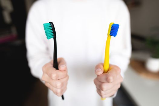 Woman's hand holds two toothbrushes. Dental direction, the subject of the morning hygiene of a married couple.