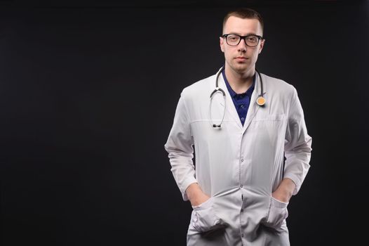 doctor in a medical mask, with a stethoscope around his neck and wearing gloves, stands in a white coat. Portrait of a doctor.