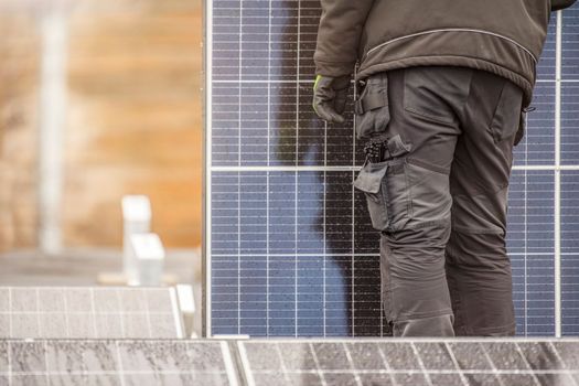 The process of installing solar panels. Solar panel installers work on the roof. Installers carry solar panel module to installation site, green and renewable energy concept.