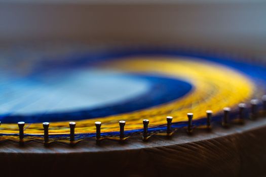 Colored thread mandala on a wooden board with nails. Mandala Moon Harmony Sun esotericism and psychology pictures from yellow and blue silk threads