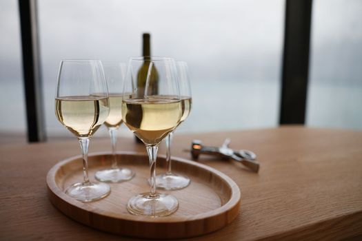 White wine in glasses standing on wooden tray closeup. Holiday with alcohol concept