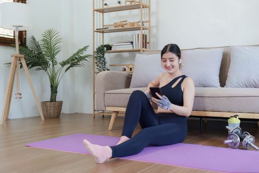 Healthy asian woman practicing relaxation yoga at home. Spending time and playing phone at home concept.