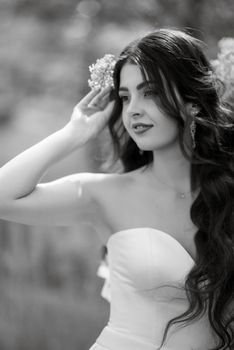 young girl bride in a white dress in a spring forest in lilac bushes on a wedding day