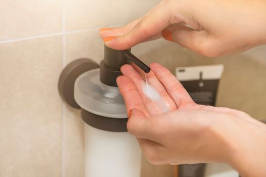 Washing and disinfecting hands, a woman uses liquid soap to wash her hands, in the bathroom, close-up. Place for text or copy space.