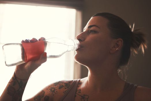 Your body cant perform if youre not hydrated. a young woman drinking water after her workout at home
