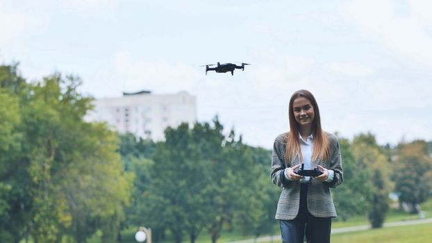 A cute girl controls a drone in the park