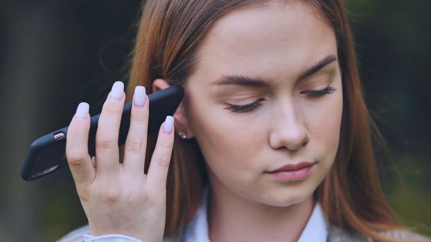 A young beautiful girl listens to an audio message on her phone