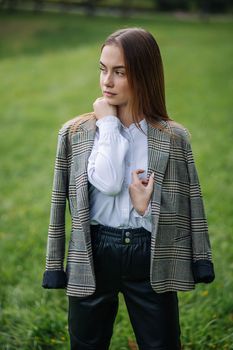 A young girl in a jacket poses in a park in the summer