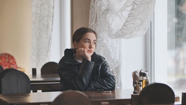 A lonely young girl sits in a cafe