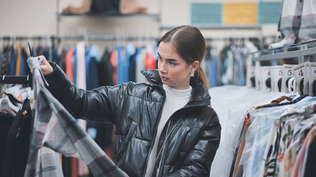 A young girl choosing and looking at clothes in the store