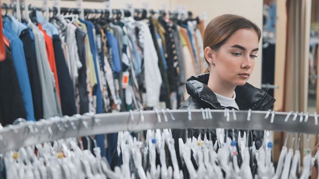 A young girl choosing and looking at clothes in the store