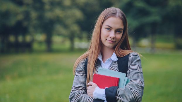 A smiling student with books in the park