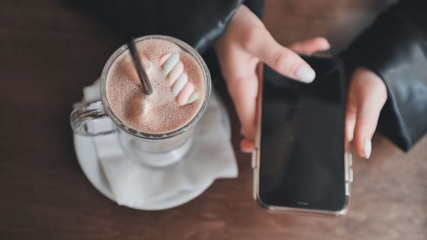 The girl is about to drink cuppuccino and lays down her smartphone