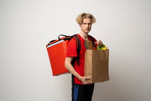 Sive view handsome delivery man, courier carrying package bag of grocery food and drinks from store, supermarket isolated on white studio background