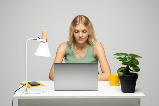 Young smiling freelancer woman using laptop for remote work in her workspace, studio. E-learning at university college, e-banking, online shopping, webinars