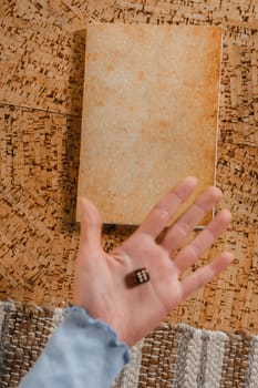 There is a dice in a person's hand. Close-up of a hand with a dice on the background of a notebook.