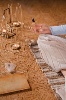 A woman is sitting in a lotus position with scented candles in her hands in the gym.