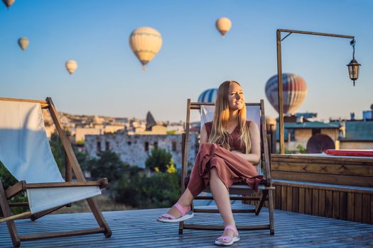 Tourist woman looking at hot air balloons in Cappadocia, Turkey. Happy Travel in Turkey concept. Woman on a mountain top enjoying wonderful view.