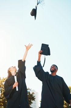 University, graduation and students with graduation cap in air for celebration, happiness and joy. College, education and man and woman throw hats after achievement of degree, diploma and certificate.