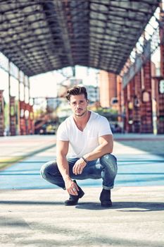 Handsome man in city setting, a former industrial environment, under a huge metal structure