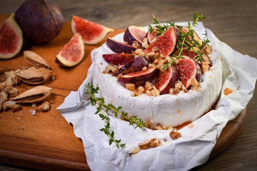 Brie cheese served on a wooden board with figs, walnuts and honey