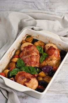 Chicken breast stuffed with goat cheese with spinach, wrapped in prosciutto, with slices of baked potatoes, tomatoes, and dried prunes.
