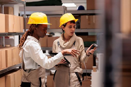 Diverse woman storehouse managers scanning parcels for stock monitoring. Warehouse workers using barcode scanner device for freight inventory in shipping company software