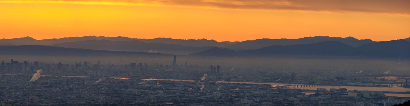 Orange glow in sky over hazy city at sunrise. High quality photo