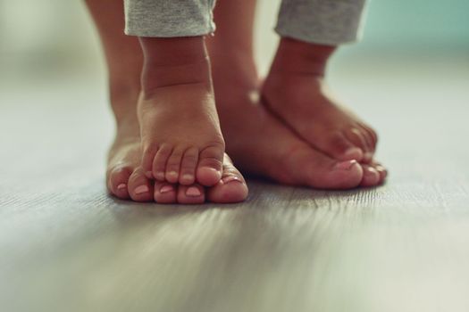 Tiny feet will one day become big, cherish these moments. an unrecognizable mothers feet and her childs feet at home