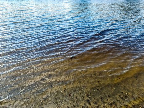 Water surface with waves and ripples and the sunlight reflecting at the surface