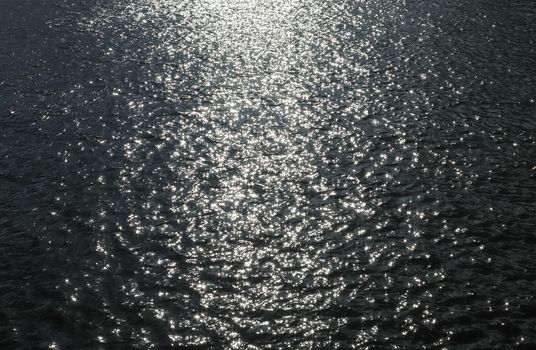 Water surface with waves and ripples and the sunlight reflecting at the surface