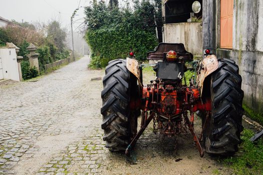 Old classic farm tractor parked in cobblestone street.