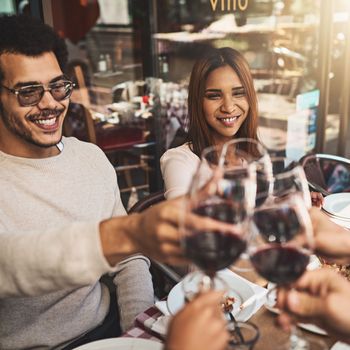 We should do this more often. a group of cheerful young friends having a celebratory toast with wine at dinner inside of a restaurant