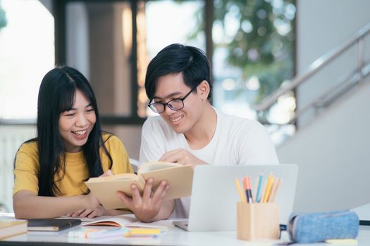 Young asian university students are studying for an exam. There are tutor books with friends. They are classmates that try to help each other. They have been tutoring for many hours in the campus.