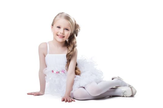 Full length portrait of beautiful little girl in dress sitting on floor. Isolated on white