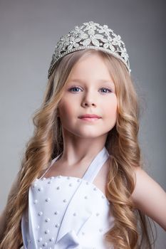 Gorgeous little girl in crown, on gray background