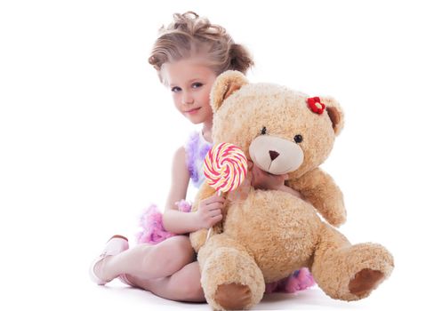 Little girl with lollipop and soft toy. Isolated on white