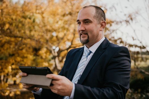 Mature entrepreneur drink coffee in autumn park. Senior executive rest in city park.