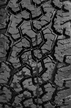Close-up of black off-road tire tread pattern background vertical.