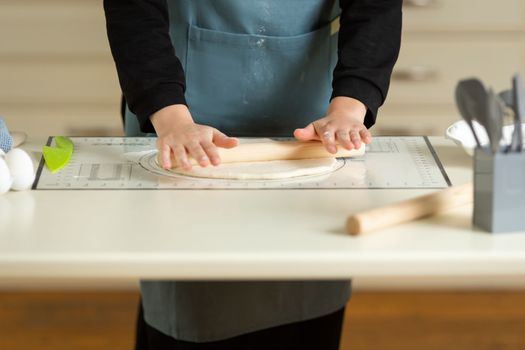 Cooking dough products on a large kitchen table on a kitchen silicone mat with copy space.