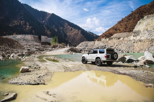 White off-road car in travel of scenic mountains with river and lake.