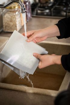 Silicone baking mat is washed under an open stream of water after cooking in the kitchen.