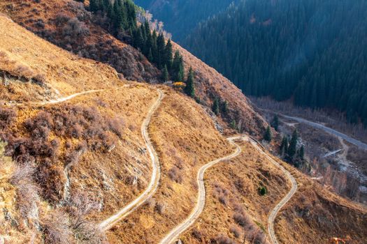 Road serpentines trail in autumn mountain gorge.