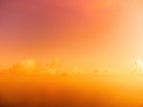 A red burning sunset with the silhouette of a cliff over the sea. Abstract nature summer or spring ocean sea background. Small waves on golden warm water surface with bokeh lights from sun.