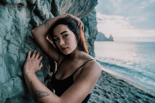 Portrait of cheerful female climber ascending a rock. The athlete girl trains in nature. Woman overcomes difficult climbing route.