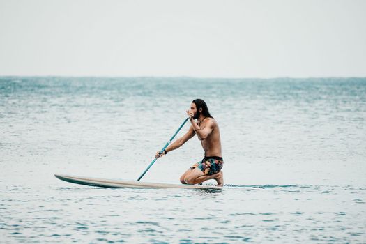 Sea woman and man on sup. Silhouette of happy young woman and man, surfing on SUP board, confident paddling through water surface. Idyllic sunset. Active lifestyle at sea or river